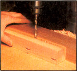 3. Con una guía de madera sobrante asegurada al banco del taladro, emplee ahora una broca de perforación de 0,95 cm (3/8") para que perfore todos los agujeros traslapados de las mortajas.