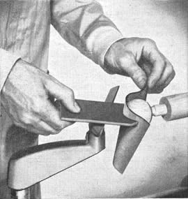 R-Haga una guía semicircular cortando un agujero de diámetro adecuado en una pieza de fibra prensada, y cortando luego ésta a lo ancho del diámetro de la perforación, la guía se usa para verificar la exactitud del torneado que se hace, y para sostener después el papel de lija que se usa en el acabado final
