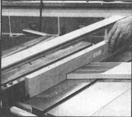 Se utiliza una tabla asegurada con abrazaderas al banco de la sierra, con el objeto de sujetar la madera contra la guía mientras se cortan ranuras en los miembros del bastidor para las tablillas