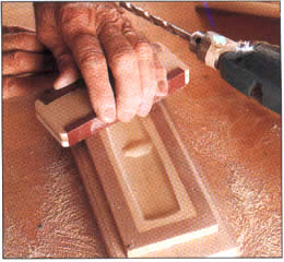 6 Después que el relleno esté duro, remueva el taladro y lije la superficie al ras con las tiras del cercado. El contorno de la cavidad sostiene al taladro con seguridad.